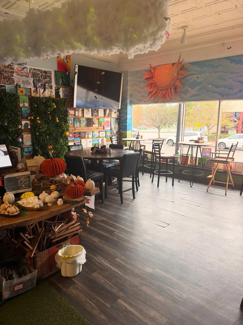 Sunlit café seating surrounded by colorful art, cloud decorations and painted murals